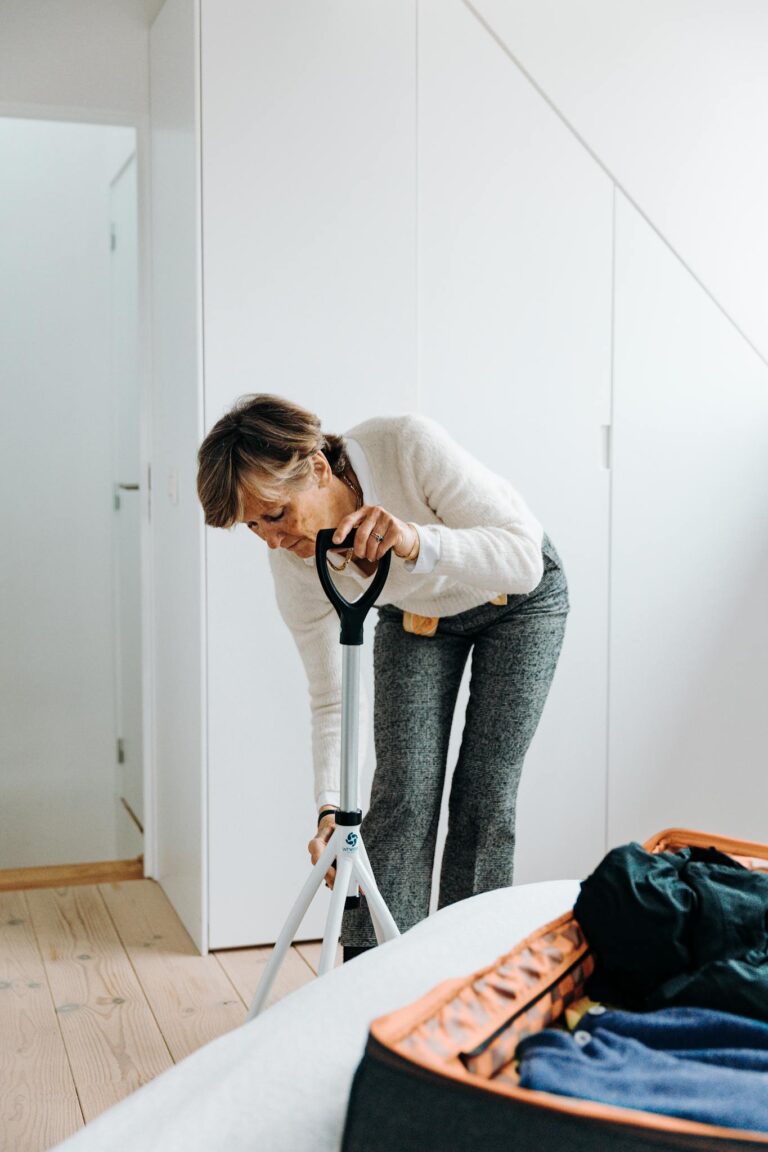 Elderly woman adjusting a rollator in a modern home setting.